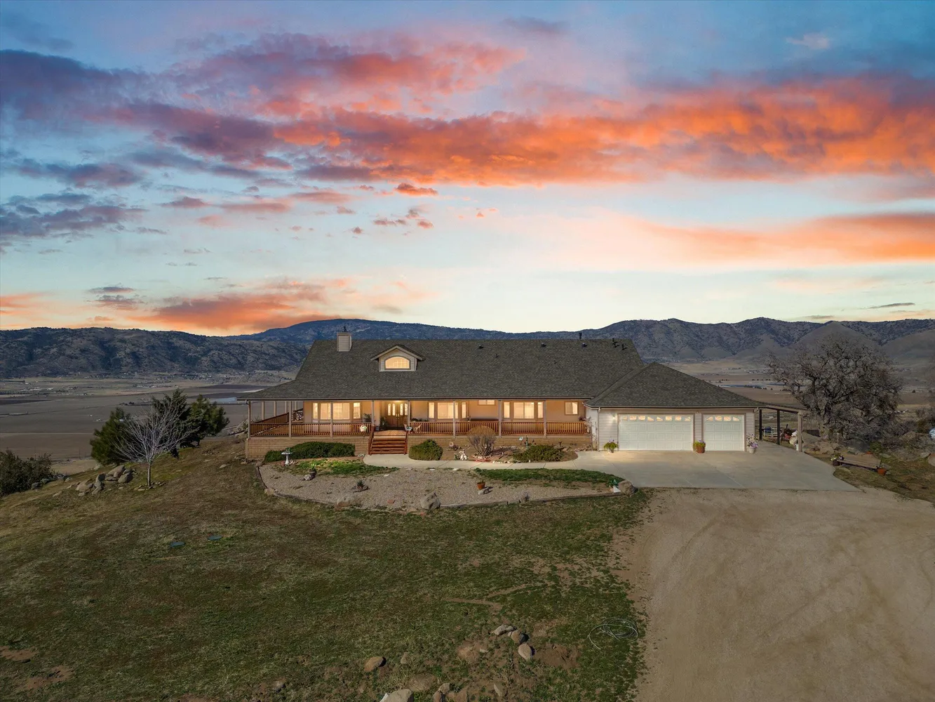 A mountain home with a wraparound porch at sunset